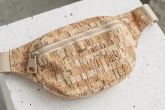 Sac banane tendance en liège texturé posé sur béton blanc, détail de matière originale et coutures fines